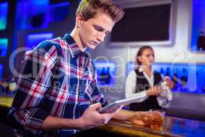 Man using digital tablet with bartender working