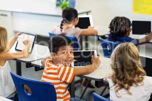 Boy with classmates using digital tablet