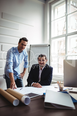 Interior designer with male coworker working on blueprint