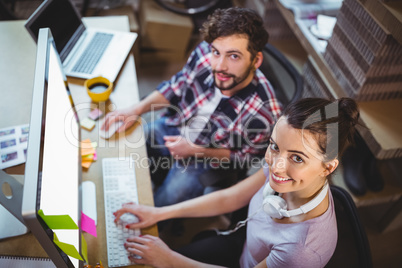 Portrait of happy coworkers working at computer desk