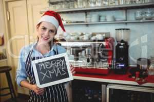 Portrait of barista holding Christmas sign at cafe