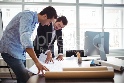 Interior designer discussing blueprint with colleague