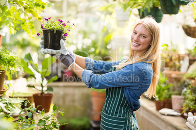 Portrait of female gardener holding flowering plant