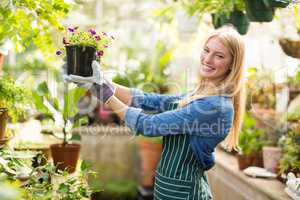 Portrait of female gardener holding flowering plant