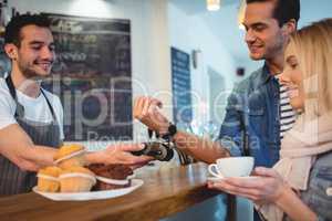 Happy customers with waiter at coffee shop