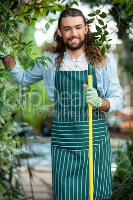 Portrait of happy worker standing with tool at garden