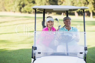 Mature golfer couple sitting in golf buggy