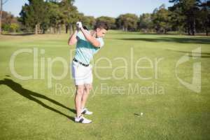 Full length of young golfer taking shot