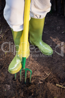 Low section of gardener with gardening fork at farm