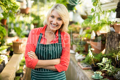 Female gardener amidst plants at greenhouse