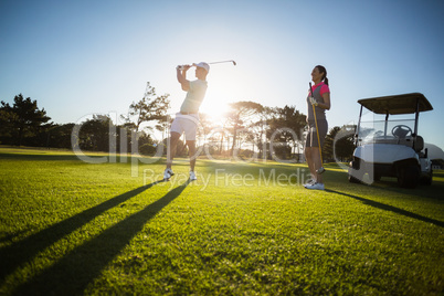 Golf player couple standing on grassy field