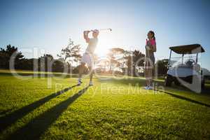 Golf player couple standing on grassy field