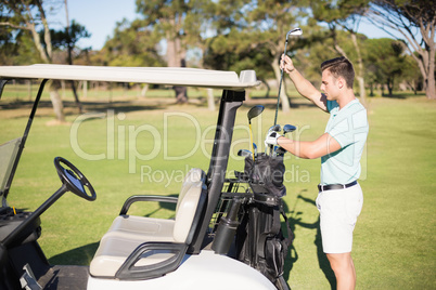 Side view of man putting golf club in bag