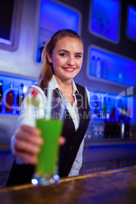 Portrait of smiling bartender serving cocktail