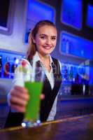 Portrait of smiling bartender serving cocktail