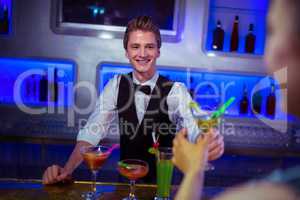 Smiling bartender serving cocktail to woman