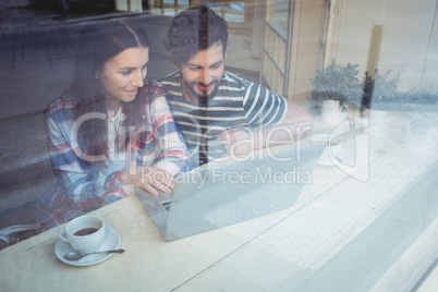 Couple using laptop with coffee at cafe