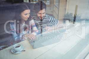 Couple using laptop with coffee at cafe