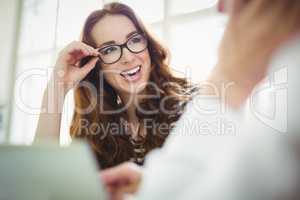 Businesswoman holding eyeglassess in creative office