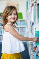 Happy girl searching books in school library