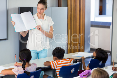 Teacher showing book to schoolchildren