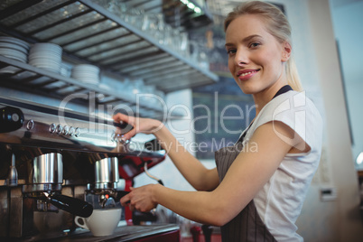 Portrait of waitress using coffee maker at cafeteria