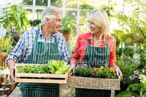 Couple holding plant crates at greenhouse