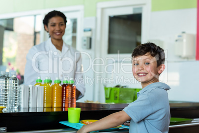 Woman with schoolboy standing at canteen counter