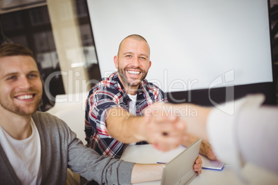 Smiling business people shaking hands in office