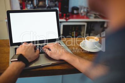 Cropped image of customer typing on laptop at cafe