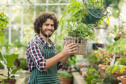 Happy male gardener holding potted plant in wicker basket