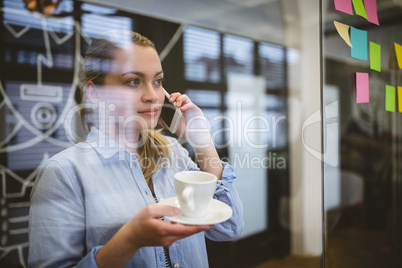 Businesswoman talking on phone during coffee break