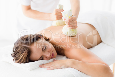 Woman receiving herbal compress massage