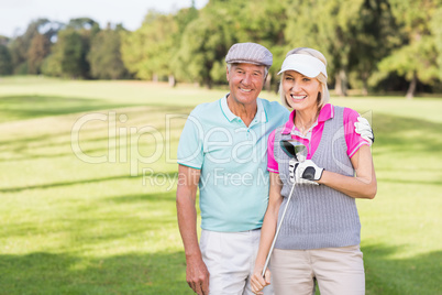 Smiling mature couple standing at golf course