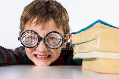 Playful boy leaning on table in classroom