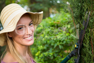 Portrait of beautiful gardener using hedge clippers at garden