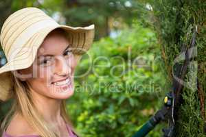 Portrait of beautiful gardener using hedge clippers at garden