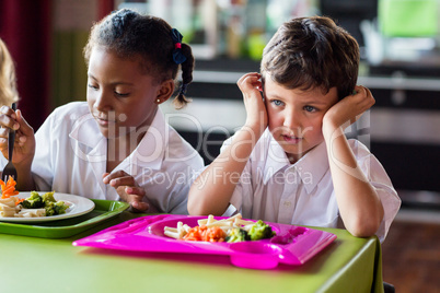 Thoughtful boy with classmates in canteen