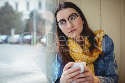 Thoughtful woman sitting with coffee at cafe