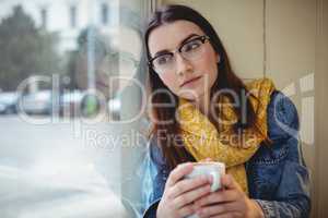 Thoughtful woman sitting with coffee at cafe