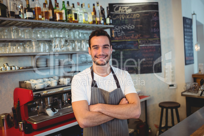 Portrait of confident barista with arms crossed at coffee shop