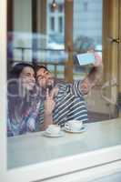 Cheerful couple taking selfie at cafeteria