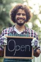 Smiling male gardener holding open sign placard