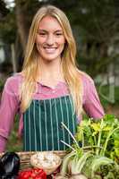Portrait of happy gardener with fresh vegetables in basket at ga