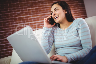 Happy woman with laptop talking on phone