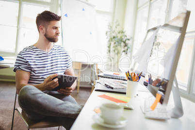 Businessman holding digital tablet while sitting in office