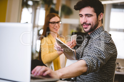 Businessman using laptop with female coworker