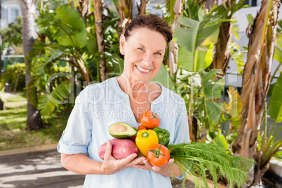 Cheerful woman holding fruits and vegetables