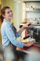 Portrait of happy waitress using espresso machine