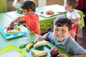 Happy boy with classmates having meal